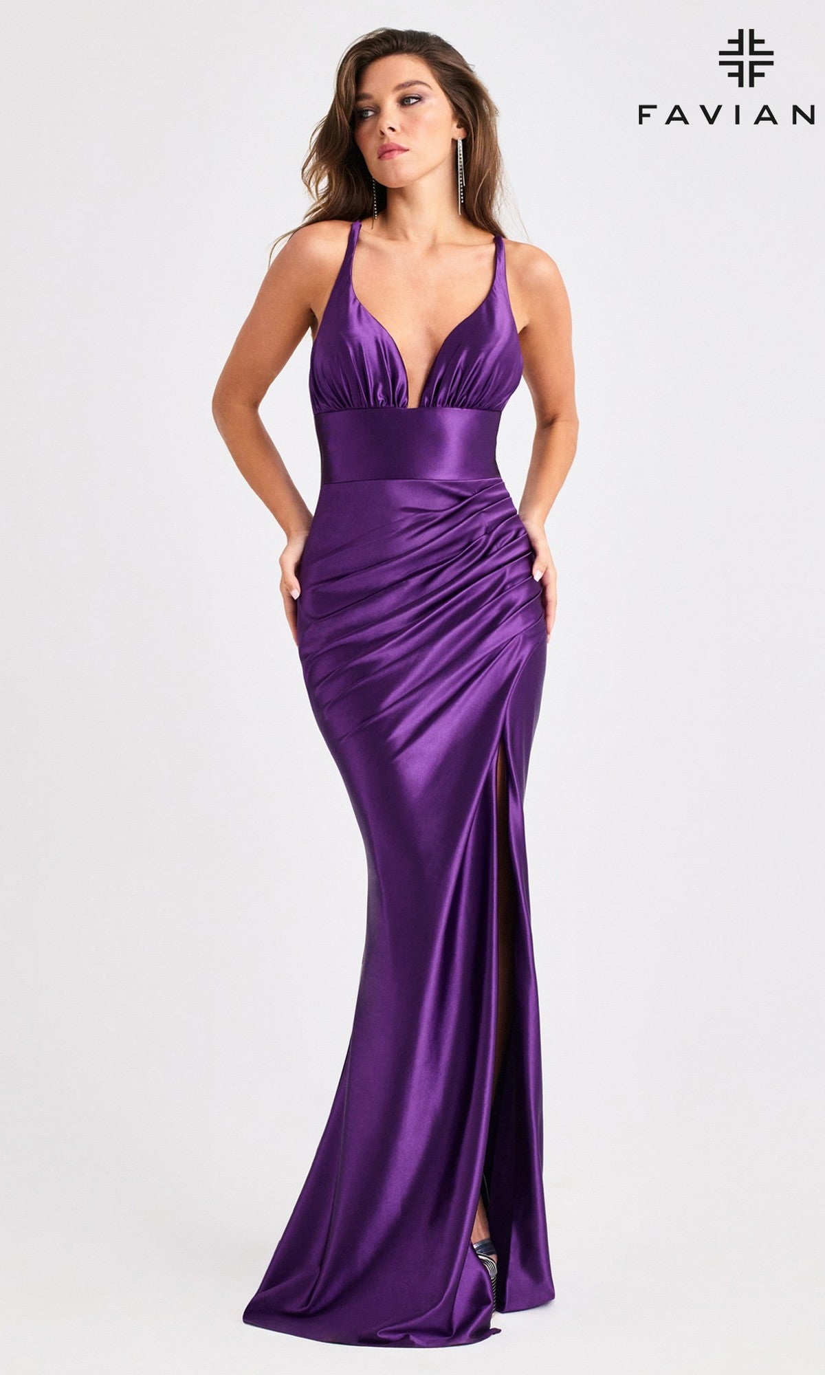 A woman wears the Faviana E11423 long prom dress—floor-length, deep purple satin with a fitted bodice, deep V-neckline, high leg slit, and lace-up open back. The background is plain with the Faviana logo in the top right corner.